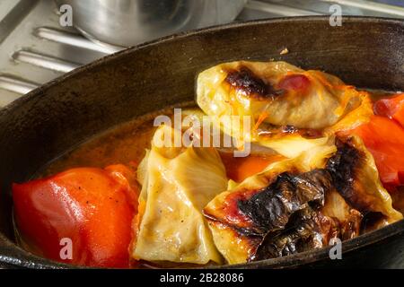 Der Gefüllte Kohl und der rote Pfeffer in Sauce. Warmes Abendessen in tiefer Pfanne auf dem Tisch Stockfoto