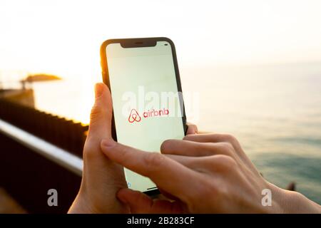 Hände, die das iPhone 11 mit einer App des airbnb-service halten. Urlaubs- und Urlaubskonzept. Eine Frau, die eine Unterkunft findet oder ein Hotel gebucht hat Stockfoto