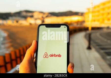 Hände, die das iPhone 11 mit einer App des airbnb-service halten. Urlaubs- und Urlaubskonzept. Eine Frau, die eine Unterkunft findet oder ein Hotel gebucht hat Stockfoto