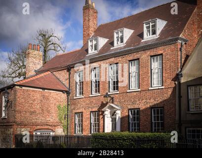 Wohnsitz des Canon of York Minster. Ein denkmalgeschützter Ziegelbau aus dem 18. Jahrhundert mit einer ornamentalen Tür. Ein Baum befindet sich im Hintergrund. Stockfoto