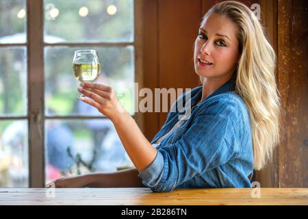 Hübsche Frau, die in der örtlichen Brauerei einen Pint Handwerkskipfel oder Bier in einem Tulpenglas hält Stockfoto