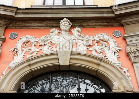 Architektonische Details in der Nähe des Hauptplatzes in Krakau, Polen, mit plastischer Büste und kunstvollem Relief über der Eingangstür. Stockfoto
