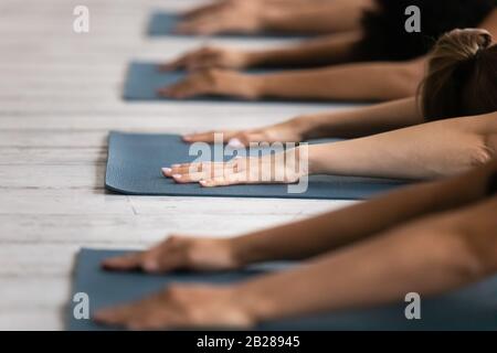 Während der Yoga-Sitzung legen Menschen auf Matten, die Kinder Asana ausführen Stockfoto