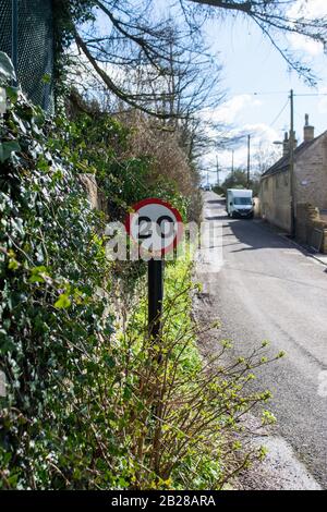 Ein Schild mit einer Höchstgeschwindigkeit von 20 mph am Rande einer schmalen Straße durch den Weiler Turleigh in Wiltshire Stockfoto