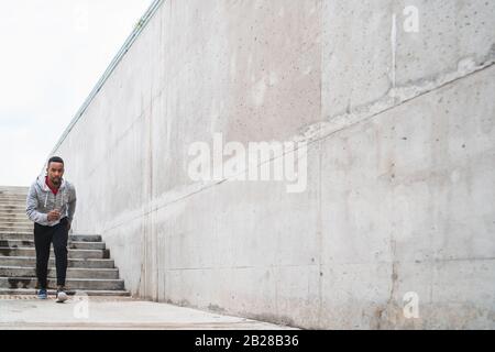 Porträt eines auf der Straße laufenden Sportmannes vor grauem Hintergrund. Sport und gesunder Lebensstil. Stockfoto