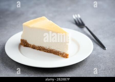 Slice of plain cheesecake on White plate and for eating isolated on betone background Stockfoto