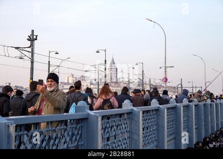 Galata, Istanbul/Türkei: Fischer auf der überfüllten Galata-Brücke mit Restaurants auf dem Unterdeck in Istanbul, Türkei. Stockfoto