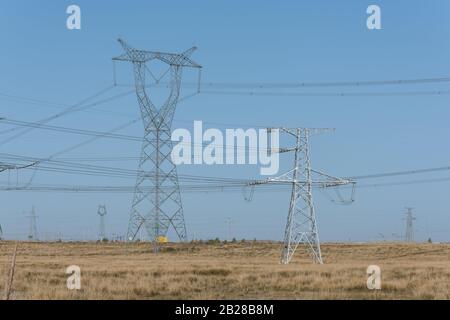 Hochspannungs-Pylone auf trockenem Grasland Stockfoto