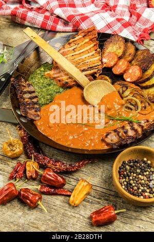 Schweinefleisch auf Stahlpfanne mit Bohnen und Spinat. Gegrilltes Fleisch in einer Bratpfanne. Kalorienfreie Lebensmittel. Fetthaltige Mahlzeit. Gebratene Kartoffeln mit Fleisch in einer Pfanne Stockfoto