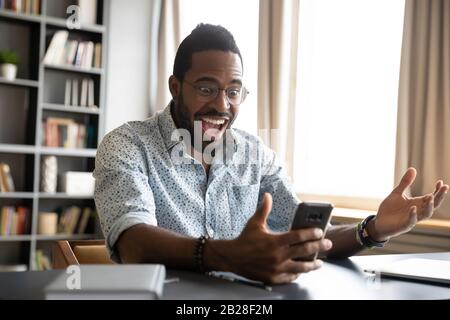 Überglücklich las der erfolgreiche junge afroamerikanische Geschäftsmann die Botschaft. Stockfoto