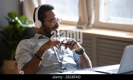 Abgelenkt von der Jobstudie fröhlicher biracial Mann, der Musik hört. Stockfoto