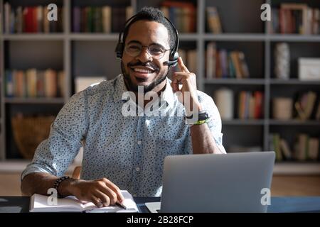 Glücklicher junger afroamerikanischer Mann, der ein Headset trägt und die Kamera betrachtet. Stockfoto