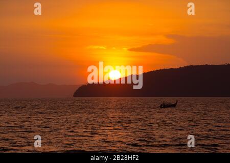 Wunderschöner tropischer Sonnenuntergang und traditionelle thailändische Bootssilhouette, Ao-Nang, Krabi, Thailand Stockfoto