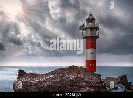 Bester Leuchtturm Punta de Teno am Atlantik - Teneriffa. Felsige Küste mit Leuchtturm, eincrepuscular Strahlen, Sonnenlicht aus den Wolken. Stockfoto