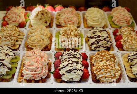 Schöne und bunte belgische Waffeln in Brüssel mit Erdbeeren, Bananen, Kiwi, Schokolade und Schlagsahne gekrönt. Stockfoto