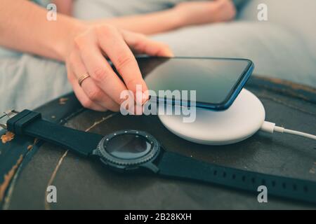 Frau händige Nahaufnahme, indem sie das Telefon auf ein drahtloses Ladegerät aufsetzt Stockfoto