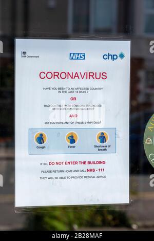 Coronavirus Warnhinweis am Fenster des Eingangs zur Arztpraxis in Westcliff on Sea, Essex, Großbritannien, mit der Bitte, dass mögliche Erkrankte nicht einreisen. Geh nach Hause 111 Stockfoto