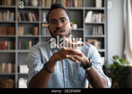Junger afrikanischer ethnischer Geschäftsmann, der Videogespräche mit Partnern abhält. Stockfoto