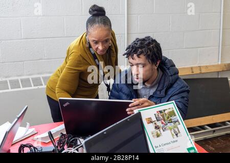 Detroit, Michigan, USA. März 2020. Juanita Brown (Standing), eine Census Job Recruiterin, hilft einem jungen Mann, sich während einer Jobmesse in der Martin Evers Missionary Baptist Church beim U.S. Census zu bewerben. Kredit: Jim West/Alamy Live News Stockfoto