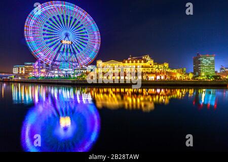 Spektakuläres Yokohama-Stadtbild des Minato Mirai District in der Nacht. Buntes Riesenrad, das sich im Lorwasser widerspiegelt. Stockfoto