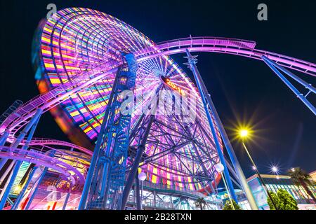 Blick auf den bunten Riesenrad und Roller Coaster, der nachts im Minato Mirai District beleuchtet wird. Stockfoto