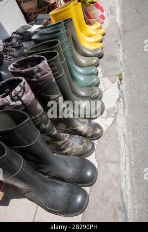 Gummistiefel auf dem Straßenbelag fotografiert. Es hat gelbe und dunkelgrüne Farben. Stockfoto