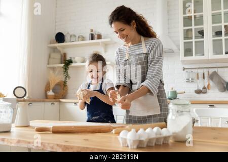 Fröhliche Mutter und kleines Mädchen backen zusammen in der Küche Stockfoto