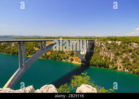 Stahlbetonauto lange hohe Bogenbrücke über den Fluss Krka in Kroatien bei Sibenik. Malerische kroatische Flusslandschaft im Frühling Stockfoto