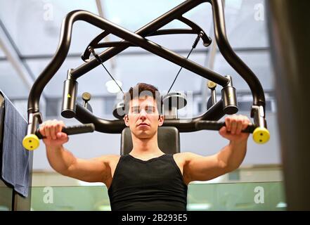 Mann, der einen Thorax-Pressmaschine in einem Fitnessstudio verwendet Stockfoto