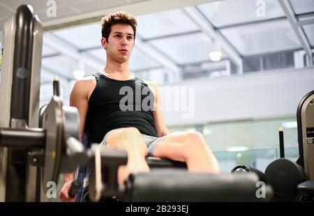 Fitness-Studio sitzender Bein-Curl-Fitness-Mann im Fitnessstudio Stockfoto
