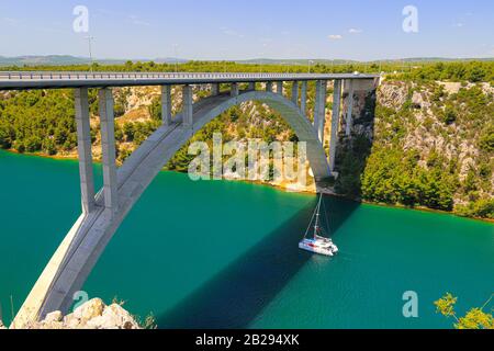 Stahlbetonauto lange hohe Bogenbrücke über den Fluss Krka in Kroatien bei Sibenik. Malerische kroatische Flusslandschaft im Frühling Stockfoto