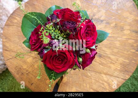 Eine kleine Vase aus roten Rosen und anderen Blumen bildet ein dekoratives Herzstück. Stockfoto