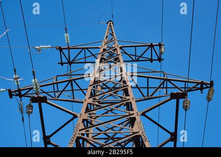 Fragment eines Metallturms mit Stromleitungen gegen einen blauen Himmel Stockfoto