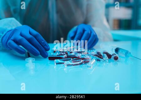 Nahaufnahme der Wissenschaftler, die Blutproben sortieren, während sie an medizinischen Forschungen im Labor arbeiten, Kopierraum Stockfoto