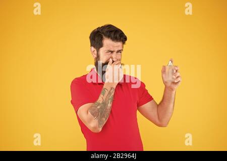 Unangenehmer Geruch. Hygiene und Gesundheit. bärtiger Mann halten Parfüm Flasche. perfektes Aroma für echte Männer. brutale hipster Geruch wählen. reifer Mann empfohlen Deodorant. Mode Köln Flasche. mag es nicht. Stockfoto