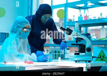 Porträt zweier Wissenschaftler, die eine vollständige Schutzausrüstung tragen und an der Forschung im medizinischen Labor arbeiten, Kopierraum Stockfoto