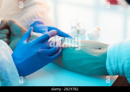 Nahaufnahme des Mediums einführen der Spritze in die Vene am männlichen Arm bei gleichzeitiger Verabreichung von Impfstoff- oder Behandlungsaufnahmen, Kopierraum Stockfoto
