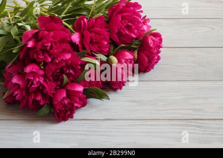 Blumenstrauß aus dunkel rosa Pfingstrosen liegen auf grau Holztisch Stockfoto