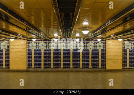 Innenansicht des Vintage-Gelb- und Blaukachelmusters an der Wand entlang der Passage der U-Bahn-Station. Stockfoto