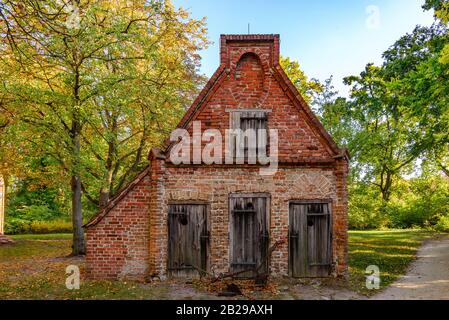 Ruhiger Blick auf das kleine, raue alte Ziegelhaus und die schmutzigen Holztüren und -Fenster, die sich im Herbst in ländlicher Umgebung befinden, ohne dass Menschen vor Sonnenuntergang dabei sind. Stockfoto