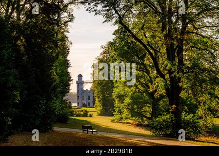 Ruhiger Blick auf die Burg auf der Pfaueninsel und Szenenatmosphäre bei Sonnenuntergang über dem Park auf der Pfaueninsel in Berlin. Stockfoto