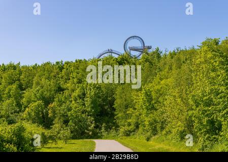 Die Sonne der Menschen läuft, spazieren und steigen in einer spiralförmigen Stahlskulptur mit dem Namen "Tiger and Turtle" oder "Magic Mountain" auf dem Hügel im Anger Park. Stockfoto
