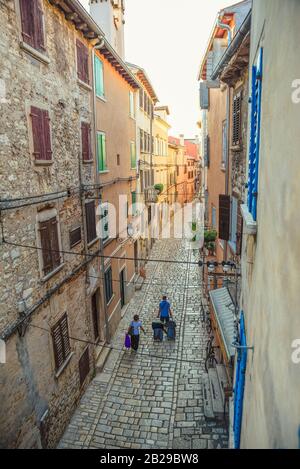 Zwei Touristen packten die Ankunft oder die Abfahrt der Altstadt von Rovinj durch die enge Straße am Mittag, die in einem vertikalen Schuss gefangen wurde Stockfoto