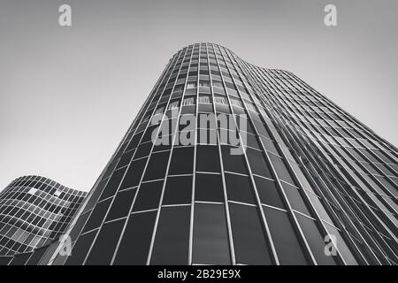 Sinuöse Glaswände eines Bürogebäudes in einem niedrigen Winkel - Schwarzweiß Stockfoto