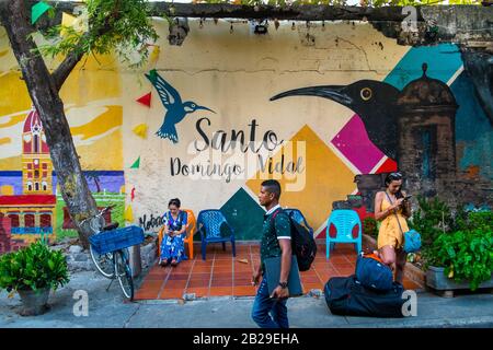 Eine weibliche Touristin steht an einer bunten Mauer im Bezirk Getsamaní, Cartagena, Kolumbien Stockfoto