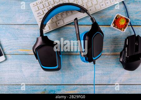 Gamepads Kopfhörer und Tastatur mit Maus auf altem Holz blau Tabelle Hintergrund. Stockfoto