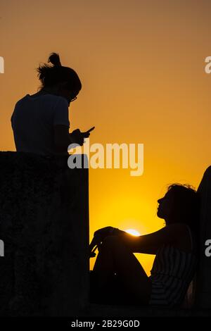 Ein Mädchen hat ihr Foto bei Sonnenuntergang auf einem Smartphone an den spanischen Wänden in Cartagena, Kolumbien aufgenommen Stockfoto