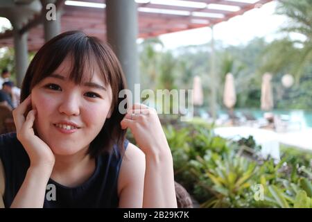 Eine schöne Dame, die sich in einem Restaurant am Pool entspannen kann. Stockfoto