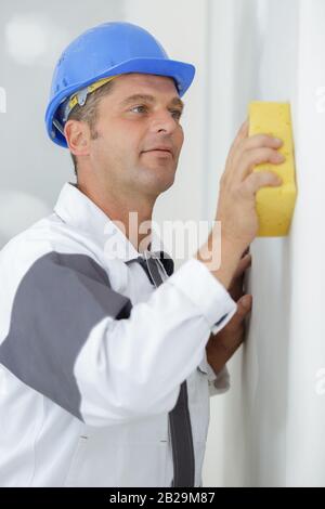 Der Mann säubert die Wand mit einem Schwamm Stockfoto