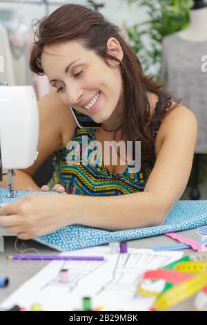 Frau näht während des Telefonierens auf der Nähmaschine Stockfoto